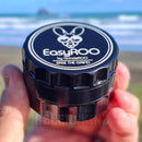 Black EasyROO grinder held by a hand with a beach in the background NZ