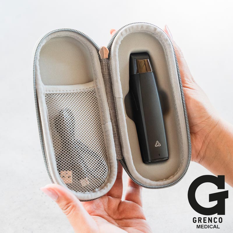 Hand holding a gray carrying case with a black device inside, featuring the Grenco Medical logo.